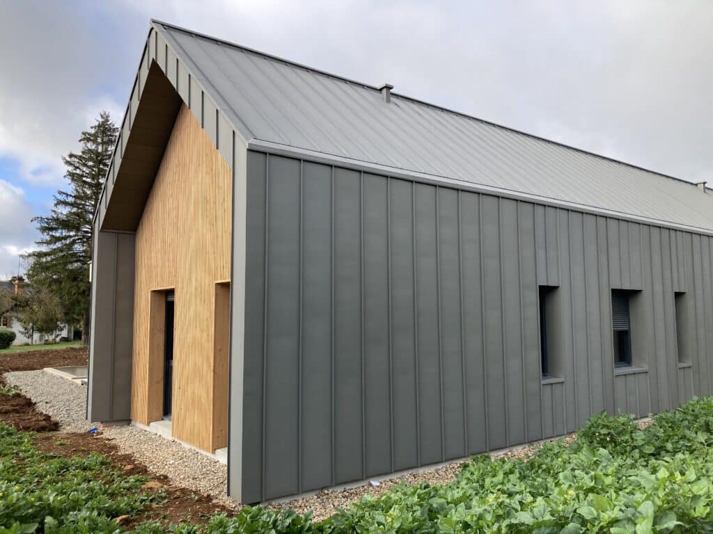 Bardage Métal Gris et Bois : Design Moderne et Toiture Joint Debout. Architecture contemporaine : façade en bardage bois et métal gris anthracite. Toiture bac acier à joints debout.